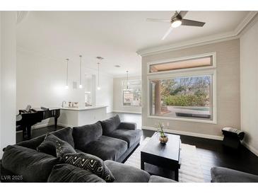 Inviting living room featuring a plush gray sofa, dark floors, and bright natural light at 11 Belfair Ct, Henderson, NV 89052