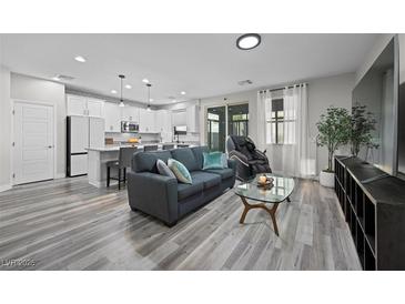 Open-concept living room featuring modern decor, sleek gray couch, and hardwood floors with bright, natural lighting at 12525 Lylan Ridge St, Las Vegas, NV 89138