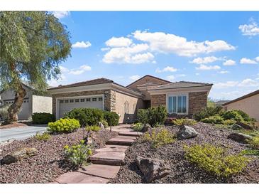 Charming single-story home featuring a stone facade, landscaped front yard, and attached garage at 2467 Moonlight Valley Ave, Henderson, NV 89044