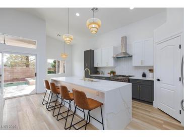 Bright kitchen with quartz countertops, stainless appliances, and large island overlooking the pool through sliding glass doors at 3957 Genoa Dr, Las Vegas, NV 89141