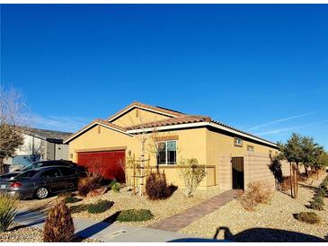 Charming single-story home with a red garage door, desert landscaping, and a blue sky above at 7910 Shimmery St, North Las Vegas, NV 89084