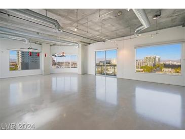 Bright, open living room features polished concrete floors and large windows with city views at 900 Las Vegas Blvd # 804, Las Vegas, NV 89101