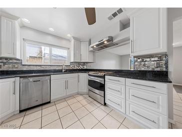 Bright kitchen featuring white cabinets, stainless steel appliances, granite countertops and neutral tile flooring at 4272 E Russell Rd, Las Vegas, NV 89120