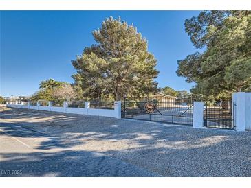 Gated property entrance with a large tree and mature landscaping under a clear blue sky at 6925 Donald Nelson Ave, Las Vegas, NV 89131