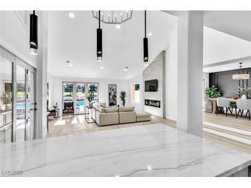 Bright open living room with fireplace, modern lighting and view of the pool at 7685 Spanish Bay Dr, Las Vegas, NV 89113