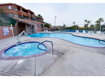 Outdoor pool and jacuzzi features a rock waterfall and mature palm trees at 555 Highland Dr # 226, Mesquite, NV 89027