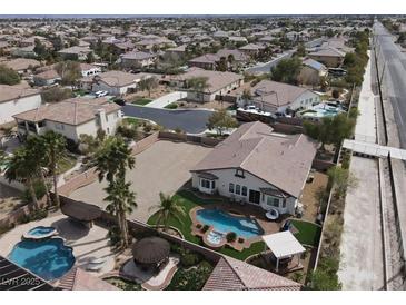 Expansive aerial view of a home featuring a pool, spa, and spacious backyard with palm trees in a residential neighborhood at 6392 Ebony Legends Ave, Las Vegas, NV 89131