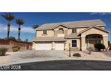 Two-story home with a three-car garage and desert landscaping under a clear blue sky at 4798 Luna Ridge Ct, Las Vegas, NV 89129