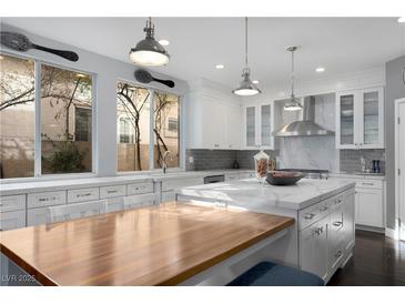 Bright, all-white kitchen featuring a large marble island, wooden dining table, and stainless steel appliances at 1404 Colony Pine St, Las Vegas, NV 89144