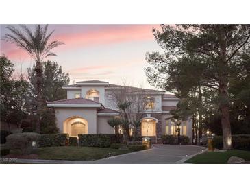 Elegant two-story home with manicured landscaping and a circular driveway, bathed in the warm colors of the setting sun at 2041 Troon Dr, Henderson, NV 89074