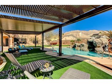 Inviting backyard oasis with a covered patio, pool with a rock feature, and mountain views at 6689 Sparks Ave, Las Vegas, NV 89142