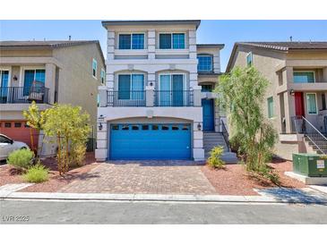 Charming three-story home featuring a blue garage door, balcony and landscaped front yard at 7665 Sandhaven St, Las Vegas, NV 89139