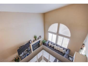 Bright living room featuring a fireplace, a comfortable couch, and a large arched window with natural light at 1933 Orchard Valley Dr, Las Vegas, NV 89142