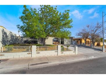 Charming single-story home featuring a well-manicured lawn and a quaint fence, complemented by a lush tree at 4258 E Twain Ave, Las Vegas, NV 89121