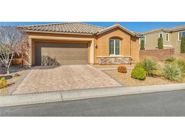 Charming home features desert landscaping, tile roof and brick driveway leading to a two-car garage at 9076 Bridal Creek Ave, Las Vegas, NV 89178