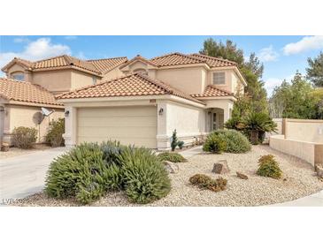 Charming two-story home with a tile roof, two-car garage, and beautifully landscaped front yard featuring desert plants and rocks at 1216 Maserati Dr, Las Vegas, NV 89117