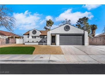 Charming one-story home featuring a gray garage door, white exterior, and well-maintained yard at 1905 Joella St, Las Vegas, NV 89108