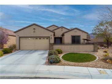 Attractive home exterior with a two-car garage, mature landscaping, and stone accents at 2392 Mystic Star St, Henderson, NV 89044