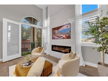 Bright living room boasts high ceilings, a fireplace, and access to outdoor patio at 41 Via Verso Lago, Henderson, NV 89011