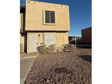 Tan two-story townhome with rock landscaping, steel security door, and window bars at 800 N Torrey Pines Dr, Las Vegas, NV 89107