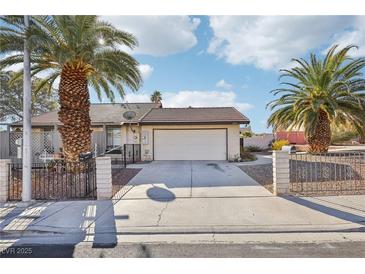 Charming single-story home featuring a wide driveway, two-car garage, and mature palm trees in a sunny setting at 8805 Pavia Dr, Las Vegas, NV 89117