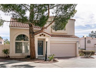 Charming townhome with tile roof, blue door, and two-car garage provides great curb appeal at 8872 Hampton Green Ave, Las Vegas, NV 89129