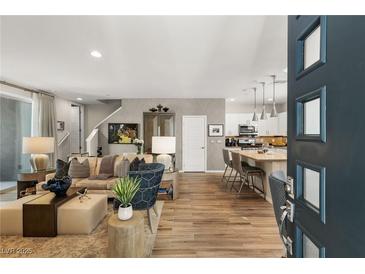 Open-concept living room with stylish furnishings and wood-look tile flooring extending to the kitchen at 11256 Rainbow Peak Ave # 207, Las Vegas, NV 89135