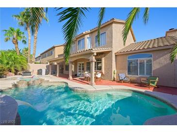 A beautiful backyard pool with lush landscaping and a covered patio at 1426 Clipperton Ave, Henderson, NV 89074