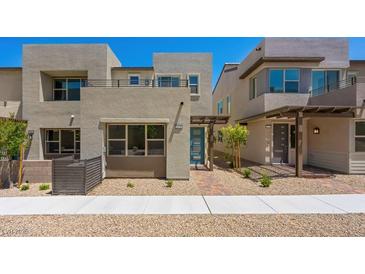Modern townhome with stucco exterior, blue door, minimalist landscaping, and second story balcony at 1479 Melodic Lark Dr, Las Vegas, NV 89138