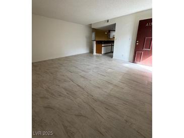 Open-concept living room featuring light, wood-look tile flooring and a view into the kitchen at 2080 Karen Ave # 15, Las Vegas, NV 89169