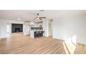 Open-concept living area featuring hardwood floors, a modern kitchen with a breakfast bar, and a stylish fireplace at 4954 Palmyra Ave, Las Vegas, NV 89146