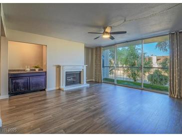 Bright living room featuring hardwood floors, fireplace, and a large window with natural light at 725 N Royal Crest Cir # 213, Las Vegas, NV 89169