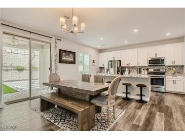 Open dining area with a large wooden table, bench seating, and access to the outdoor space at 8125 Skye Vineyard Dr, Las Vegas, NV 89166