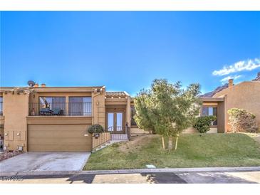 Charming home featuring a two-car garage, second story balcony, landscaped yard, and beautiful desert landscaping at 536 Greenbriar Pl, Boulder City, NV 89005