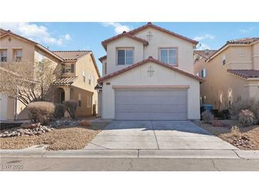 Beige two-story home featuring a two-car garage and low-maintenance desert landscaping at 7452 Wine Creek St, Las Vegas, NV 89139