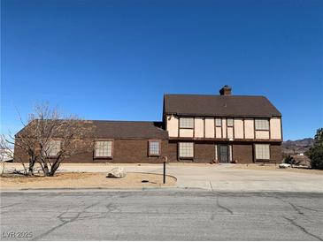 A brick and beige two story home with a brown roof sits beneath a clear blue sky at 1212 Santa Ynez Ave, Henderson, NV 89002