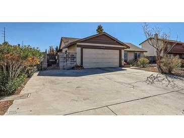 Charming single-story home showcasing a two-car garage, mature landscaping, and a spacious driveway at 2375 Rawhide St, Las Vegas, NV 89119