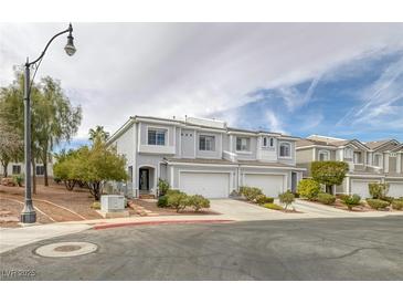 Charming townhome featuring a well-maintained, light gray exterior with a two-car garage and manicured landscaping at 2405 Esteem Ridge Dr, Henderson, NV 89052
