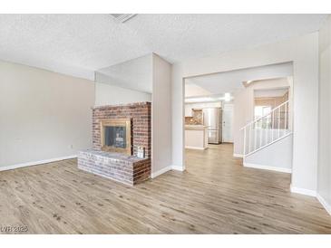 Inviting living room with a brick fireplace and light hardwood floors at 2647 Jacyra Ave, Las Vegas, NV 89121