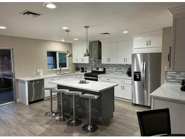 Bright kitchen featuring a gray island with marble countertop and stainless steel appliances at 3908 Redwood St, Las Vegas, NV 89103