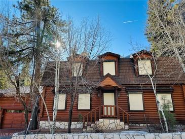 Charming wood cabin featuring a stone wall, a well maintained lawn, and lush trees at , Mount Charleston, NV 89124