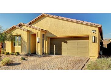 Charming single-story home featuring a brick driveway, two-car garage, and low-maintenance desert landscaping at 3026 English Palmer Rd, North Las Vegas, NV 89086