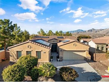 Charming single-story home with desert landscaping, two-car garage, and solar panels under a bright blue, cloudy sky at 5698 Hoptree Dr # 1, Pahrump, NV 89061