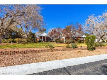 Charming single-story home with brick accents, mature trees, and a well-manicured lawn on a sunny day at 7229 Mira Vista St, Las Vegas, NV 89120