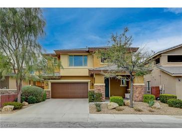 Two-story home with a two car garage, stone accents, and manicured landscaping at 10564 Tranquil Glade Ln, Las Vegas, NV 89135