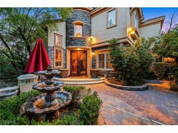 Beautiful two-story home featuring stone accents, a water fountain, mature landscaping, and a decorative entryway with double doors at 801 Sir James Bridge Way, Las Vegas, NV 89145