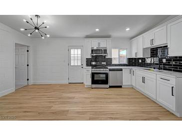 Bright kitchen features white cabinets, stainless steel appliances, and black tiled backsplash at 2512 Taylor Ave, North Las Vegas, NV 89030