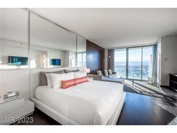 Modern bedroom with a king-size bed, sitting area, and city views through large windows at 4381 W Flamingo Rd # 3303, Las Vegas, NV 89103
