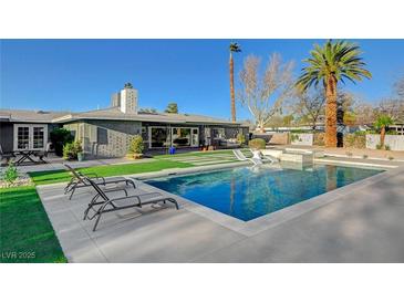 Inviting backyard pool with modern lounge chairs and green grass, perfect for relaxing and entertaining at 2711 Ashby Ave, Las Vegas, NV 89102