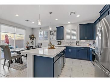 Modern kitchen features navy cabinets, stainless appliances, and a large center island with counter seating at 4733 Cactus Sun Ln, North Las Vegas, NV 89031